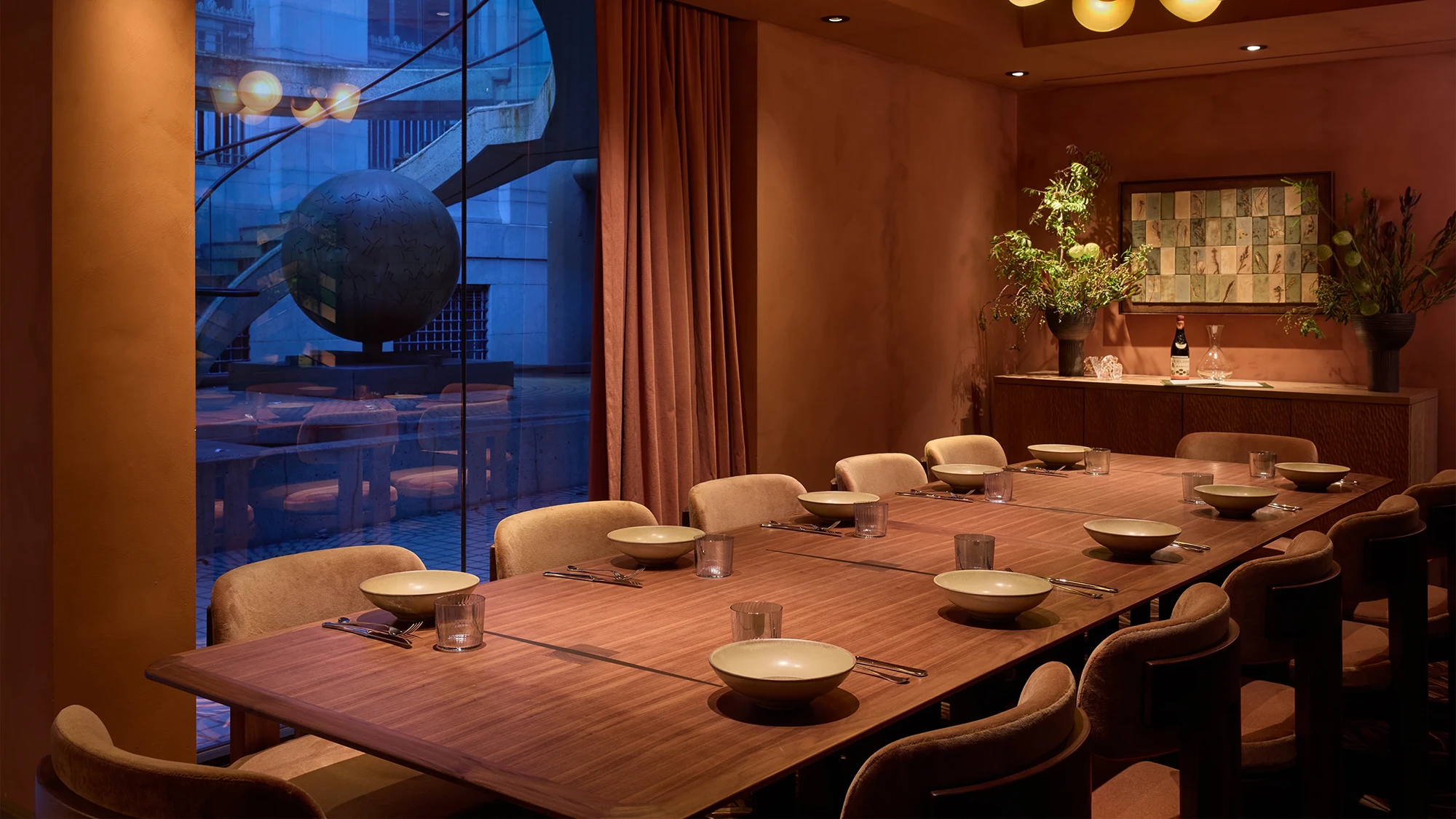 A private wooden dining table lined with plates and bespoke chairs