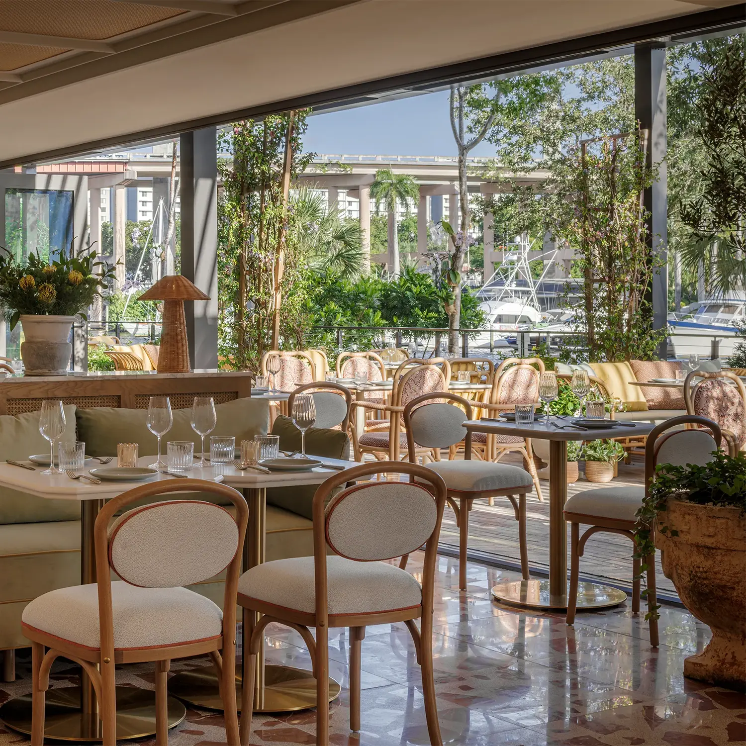 A highway bridge over water in Miami in the backdrop of a lovely indoor restaurant seating area set for service