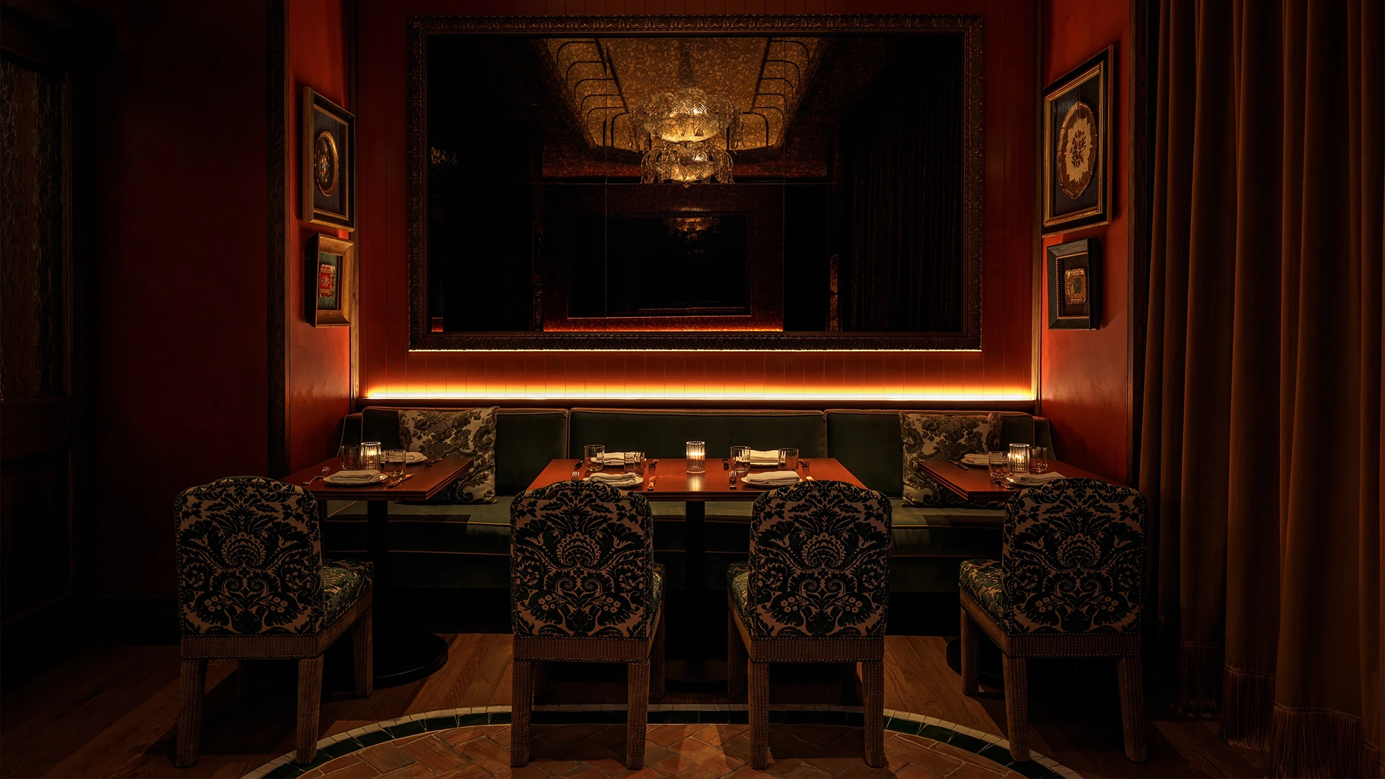 A dark corner in Erba Miami restaurant with floral upholstered chairs and red tables