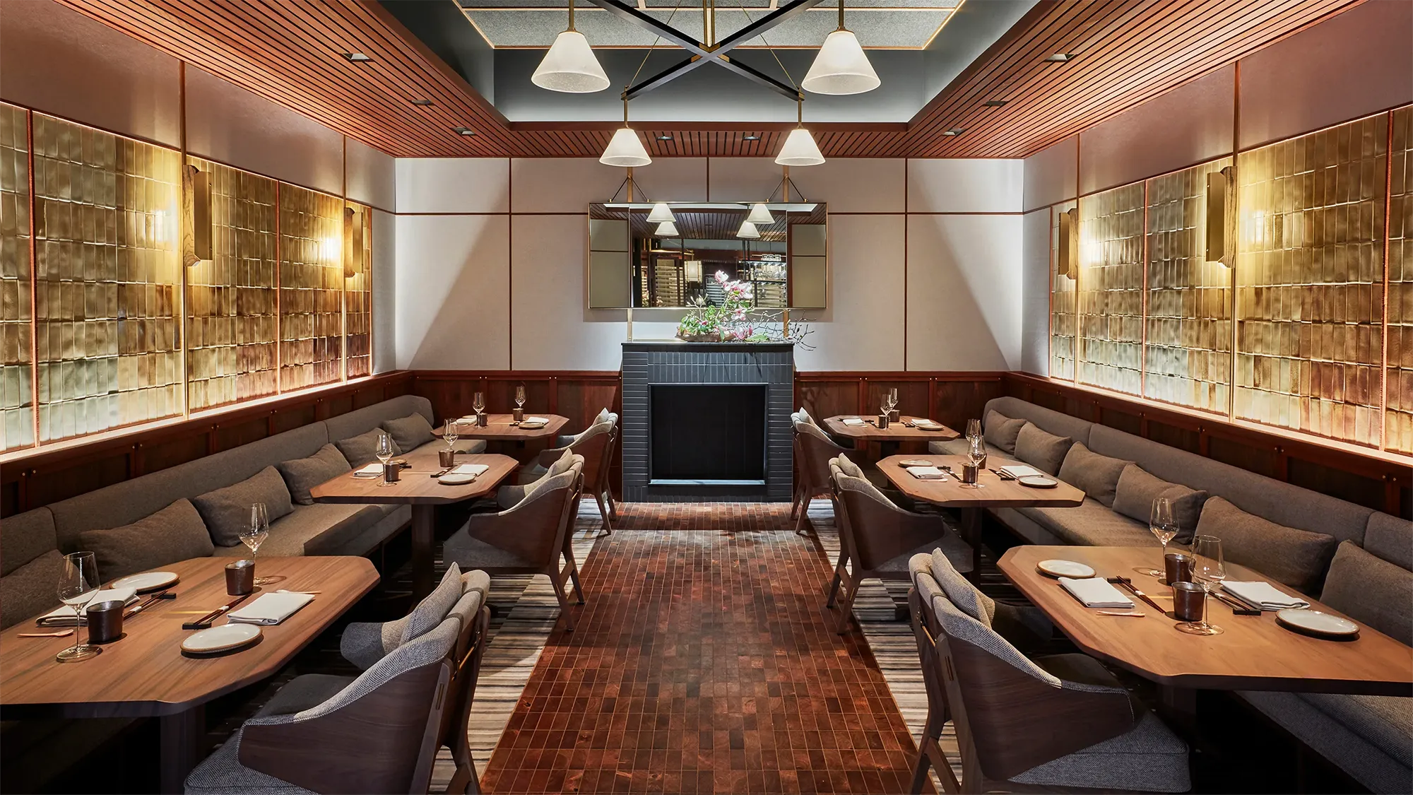 A restaurant dining room area lined with tables set for food service in a uniquely designed room centered by a fireplace