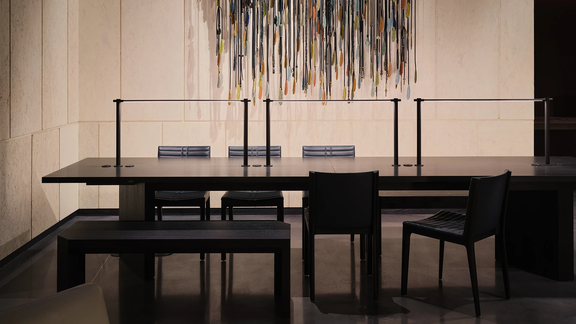 A hotel workspace with a long wooden desks and contemporary lamps