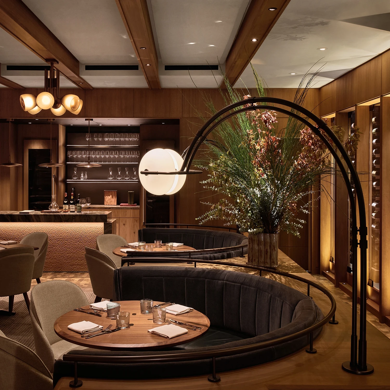 An arc lamp illuminating a half circle booth around a wooden table in a restaurant