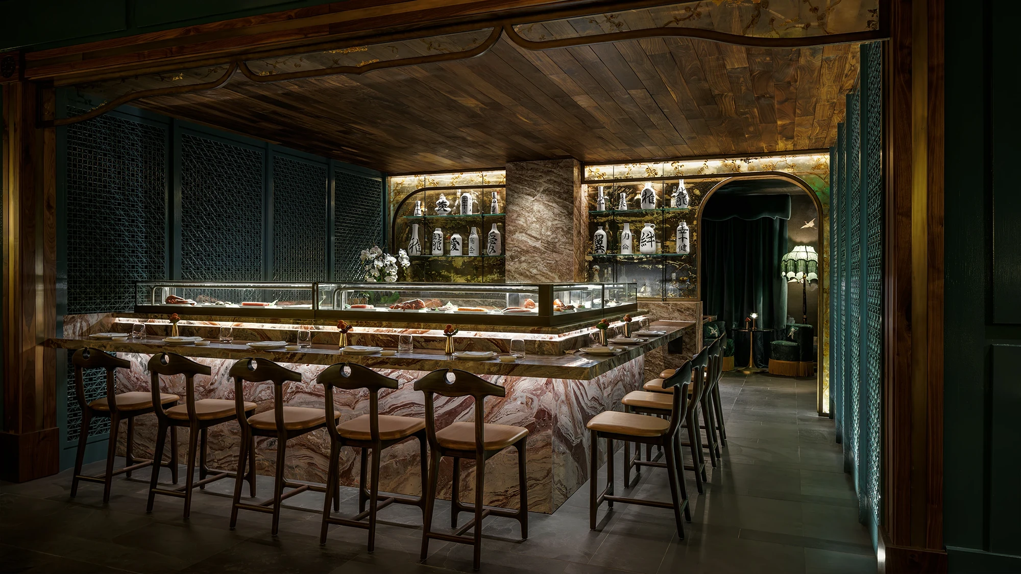 An omasake sushi bar lined with chairs viewing the glass case with fresh fish on ice