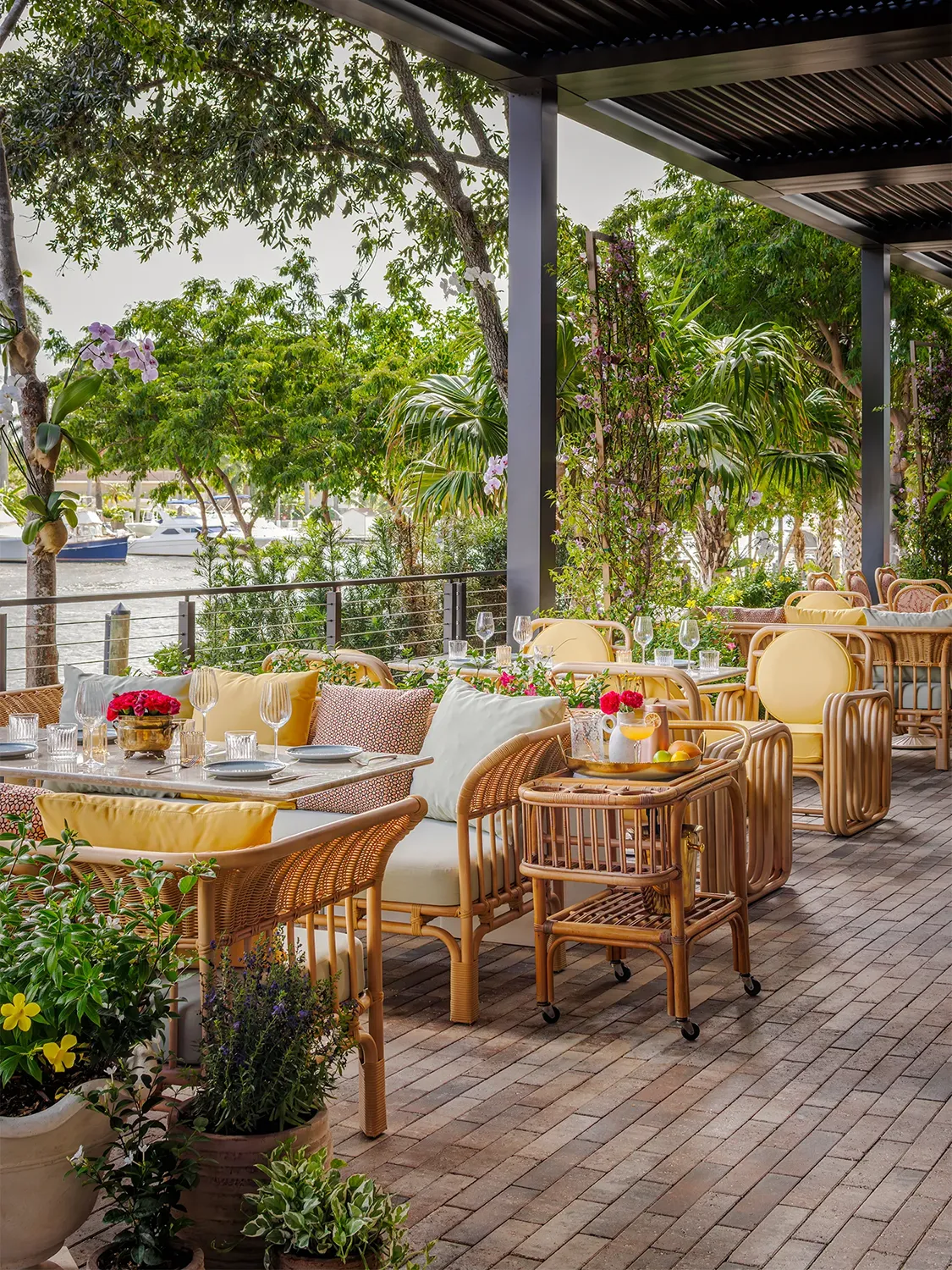 Outdoor restaurant seating with tables and wooden chairs next to a body of water in Miami 
