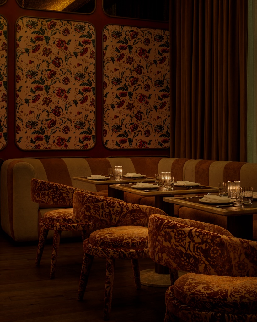 A restaurant lounge area featuring upholstered chairs and a sofa stretching across all the set tables